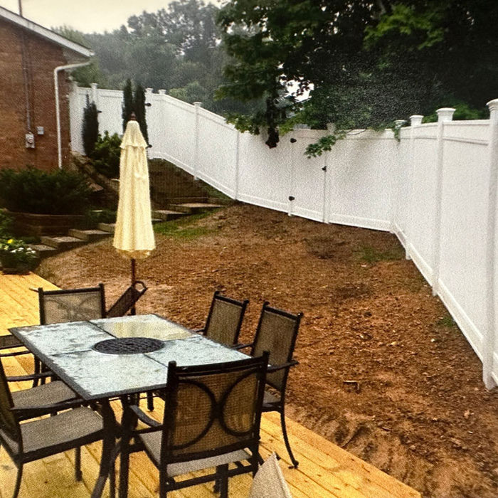 White vinyl privacy fence stepping down a backyard